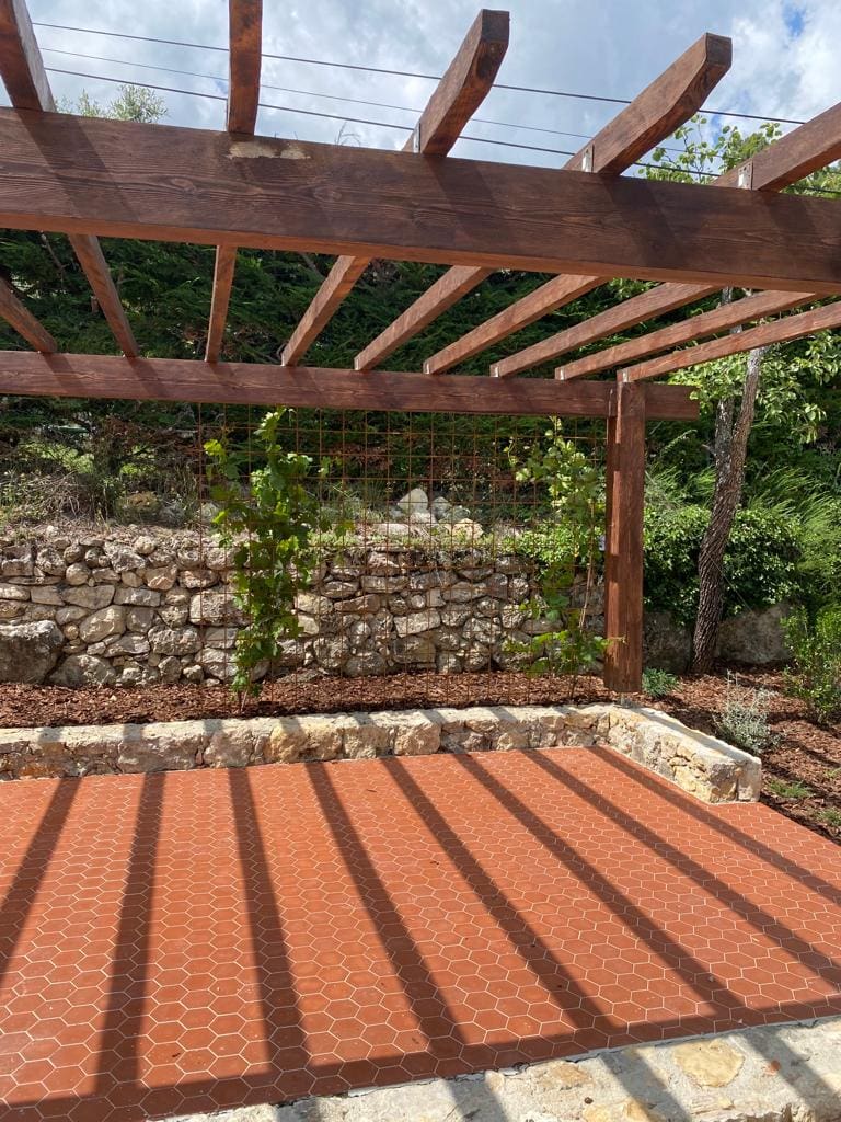 Pergola en bois sur une terrasse en carrelage avec mur de pierre à Seillans, Var